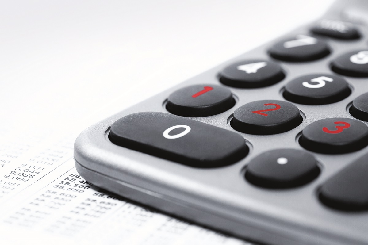 A close-up of a calculator with black buttons and red numbers, resting on printed financial documents. The numbers displayed include 0 to 3 prominently. The image emphasizes the calculator as a tool for computations, commonly used for financial tasks.