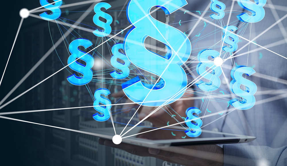 A person is using a tablet surrounded by glowing legal symbols, representing law and regulations. The background features blurred server racks, indicating a digital environment focused on legal technology. The image conveys the intersection of law and technology.