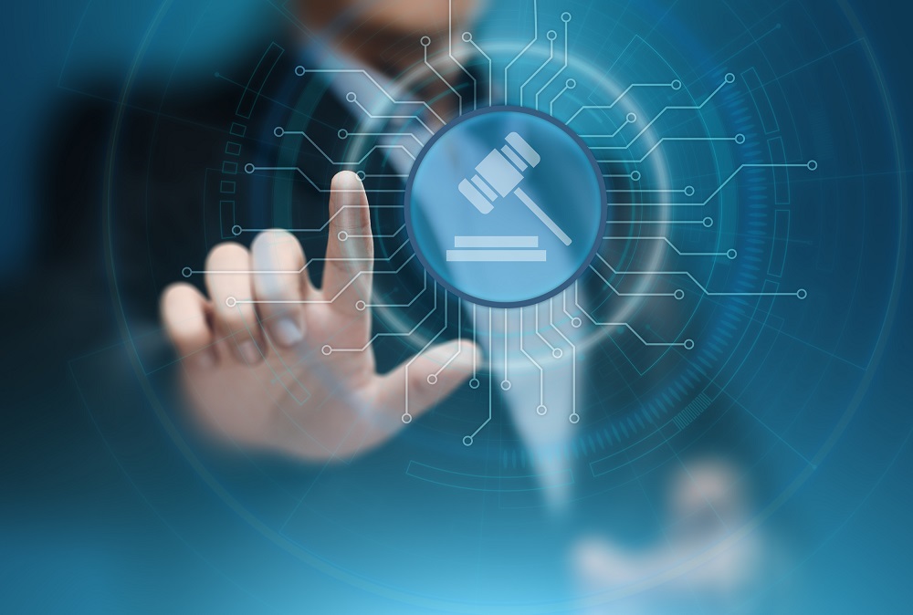 Eine Hand zeigt auf ein digitales Symbol eines Richthammers vor einem blauen, technologischen Hintergrund. Das Bild symbolisiert die Verbindung zwischen Recht und Technologie.