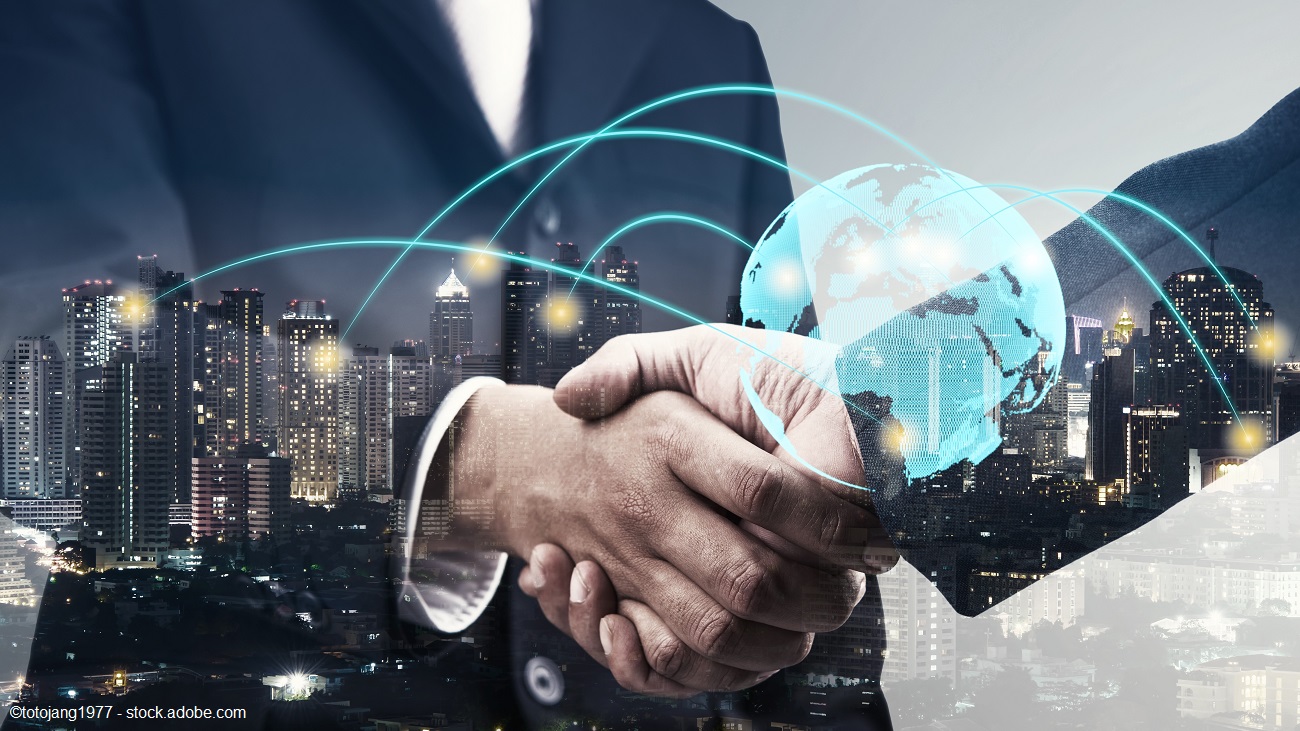 Two hands are shaking in a business agreement, symbolizing partnership and collaboration. In the background, a city skyline is visible, while digital elements, including a globe and network lines, represent global connectivity and communication in the business world.