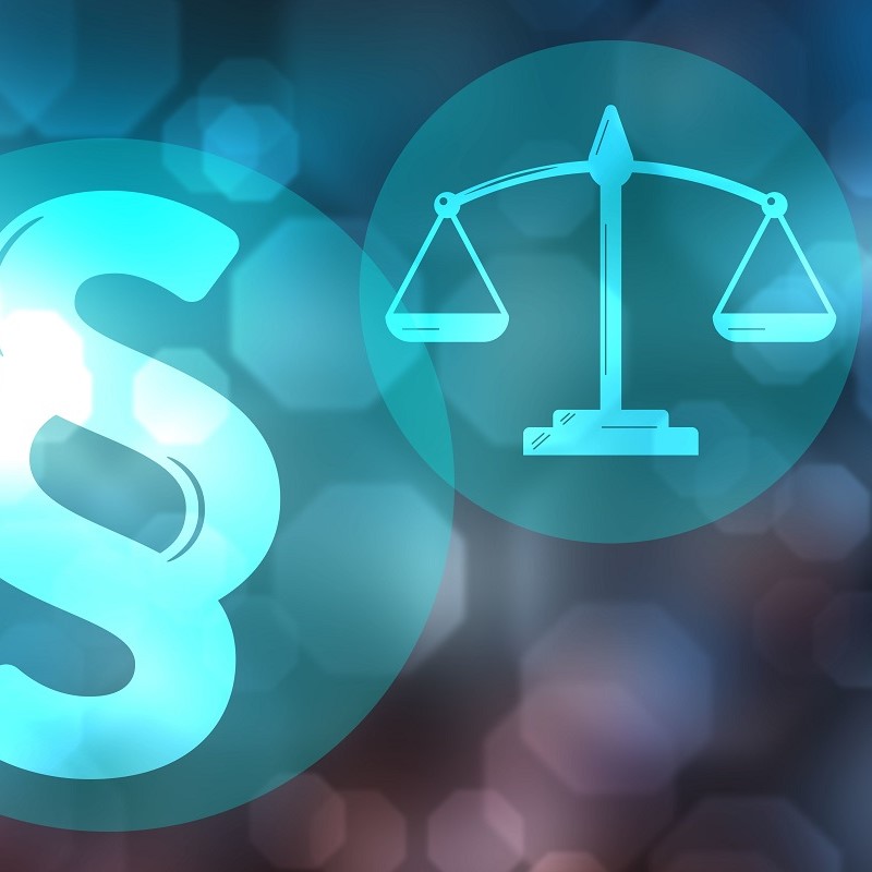 An artistic representation featuring a legal symbol (§) on the left and a scale of justice on the right, both depicted in a soft blue color against a blurred background. The image conveys themes of law and justice.