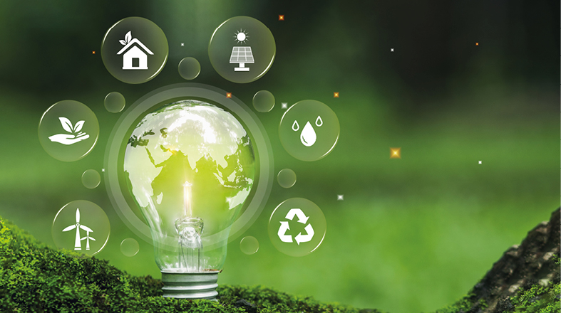 Eine Glühbirne, die eine leuchtende Erdkugel zeigt, steht auf Moos. Um sie herum sind Symbole für Nachhaltigkeit, wie ein Haus, Sonnenenergie, Wasser und Recycling, angeordnet. Das Bild vermittelt eine Botschaft über grüne Energie und Umweltschutz.
