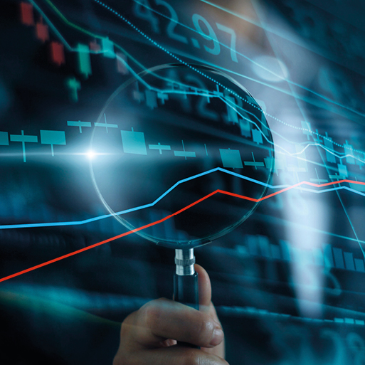 Eine Hand hält eine Lupe über ein Diagramm mit steigenden und fallenden Linien. Die Grafik zeigt Finanzdaten mit grünen und roten Balken, die Preisschwankungen darstellen. Der Hintergrund ist dunkel und hebt die Daten hervor.