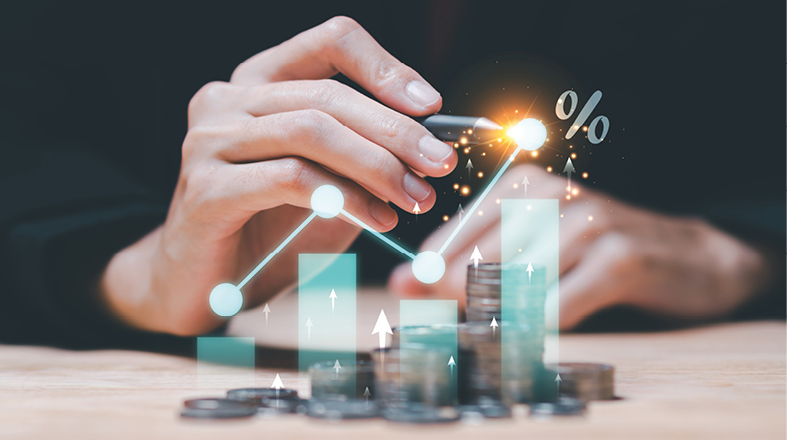 Eine Hand, die einen Stift hält, zeigt auf ein Diagramm mit aufsteigenden Säulen und symbolischen Prozentsätzen. Im Hintergrund sind Münzen zu sehen, was auf Finanzen und Wachstum hinweist.