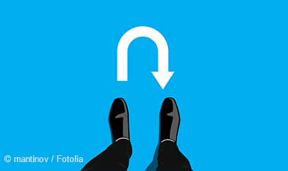 The image shows a pair of black dress shoes positioned on a blue background. Above the shoes, there is a white U-turn arrow, indicating a change in direction. The overall focus is on the theme of turning or changing course.