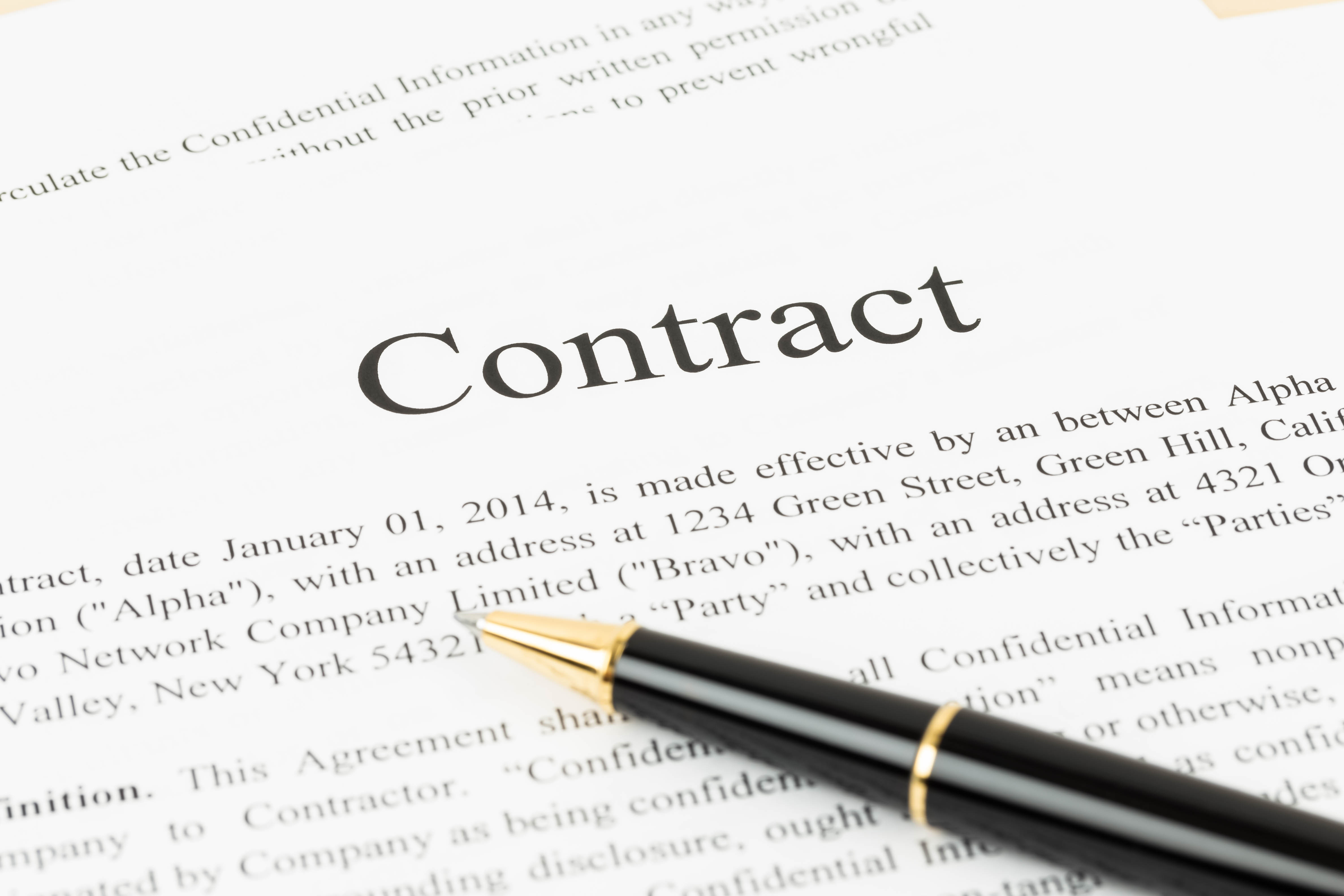 A close-up of a contract document with the word "Contract" prominently displayed at the top. A black pen rests on the document, indicating a context of signing or reviewing the agreement. The document includes legal language and terms related to the agreement.