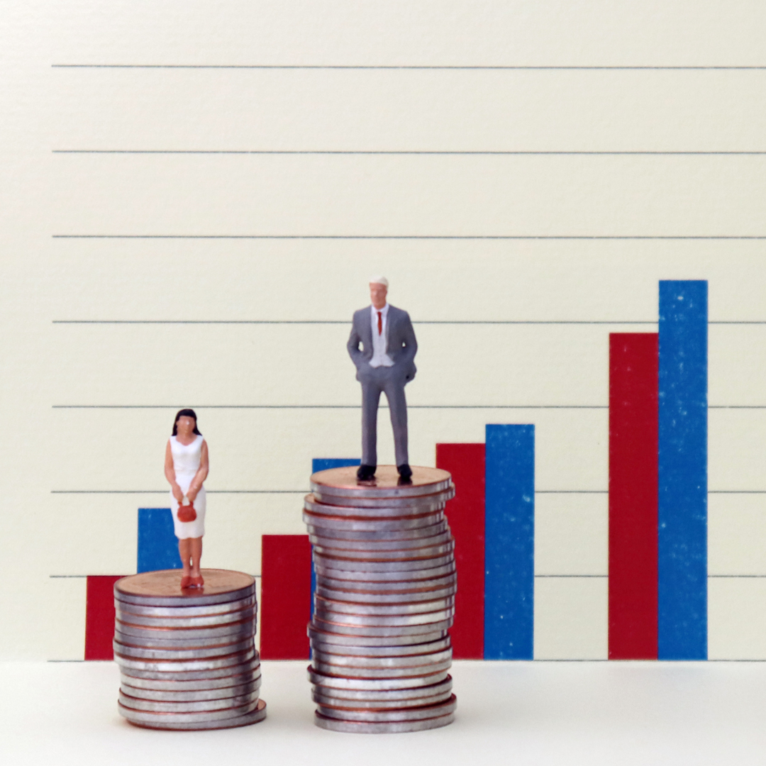 Eine Frau in einem weißen Kleid steht auf einem Stapel Münzen, während ein Mann in einem grauen Anzug auf einem höheren Stapel steht. Im Hintergrund sind steigende Balkendiagramme in Rot und Blau zu sehen, die unterschiedliche Werte darstellen.