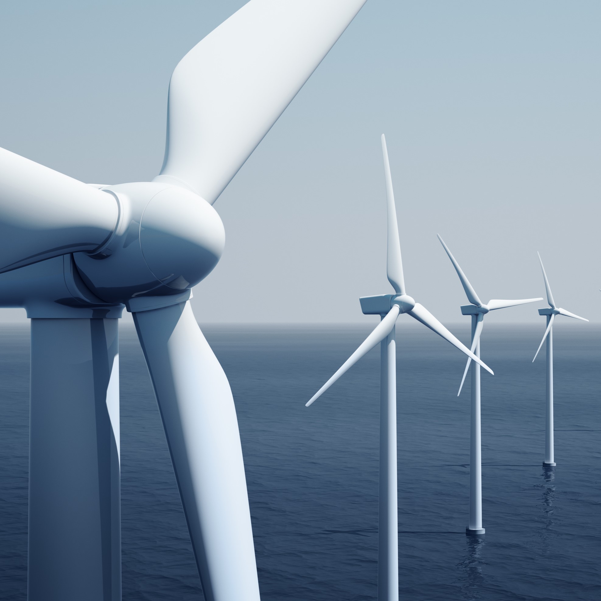 A close-up view of wind turbines situated in the ocean, showcasing sleek, white blades rotating against a clear blue sky. The image emphasizes sustainable energy production and the serene maritime environment surrounding the turbines.