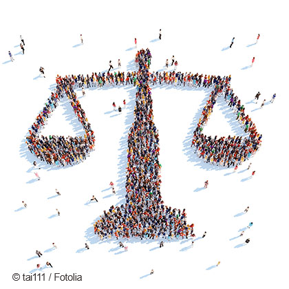 A large group of people gathered to form the shape of a balance scale, symbolizing justice. The crowd is diverse and spread out, emphasizing the unity and collective effort in advocating for fairness and equality.