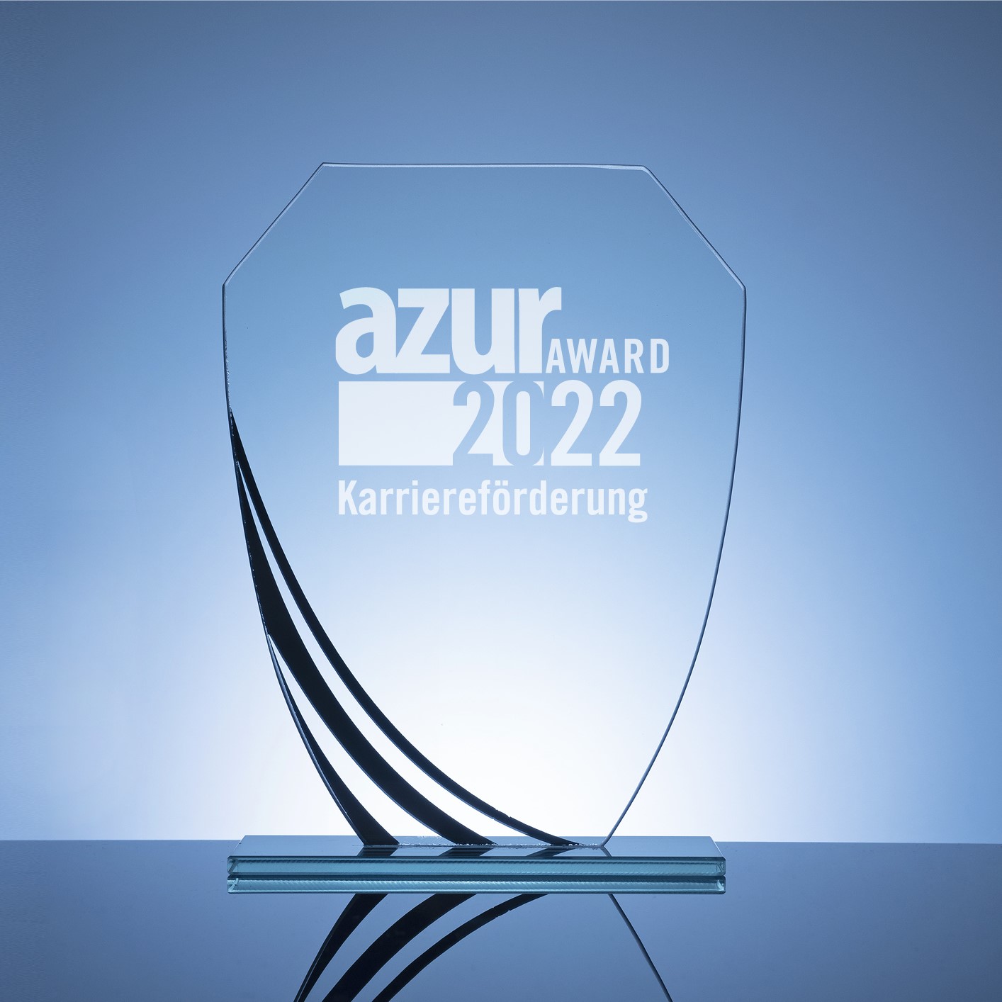 Ein transparenter Glasawards mit der Aufschrift „azur AWARD 2022 Karriereförderung“. Der Preis hat eine moderne, geschwungene Form und steht auf einem stabilen Glasfuß, vor einem hellblauen Hintergrund.
