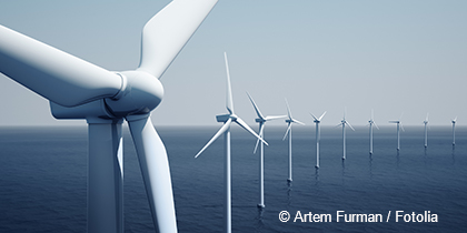The image shows a row of wind turbines in the ocean, generating renewable energy. The turbines have large white blades that rotate in the wind, contributing to a sustainable environment. The scene is set against a calm, light blue sky.
