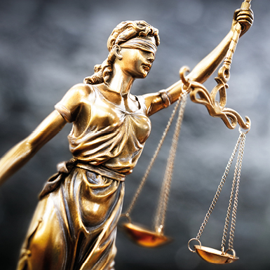Eine goldene Statue der Justitia, blind gefaltet mit einer Augenbinde, hält in der einen Hand eine Waage und in der anderen ein Schwert. Symbolisiert Gerechtigkeit und Gleichgewicht im Rechtssystem.