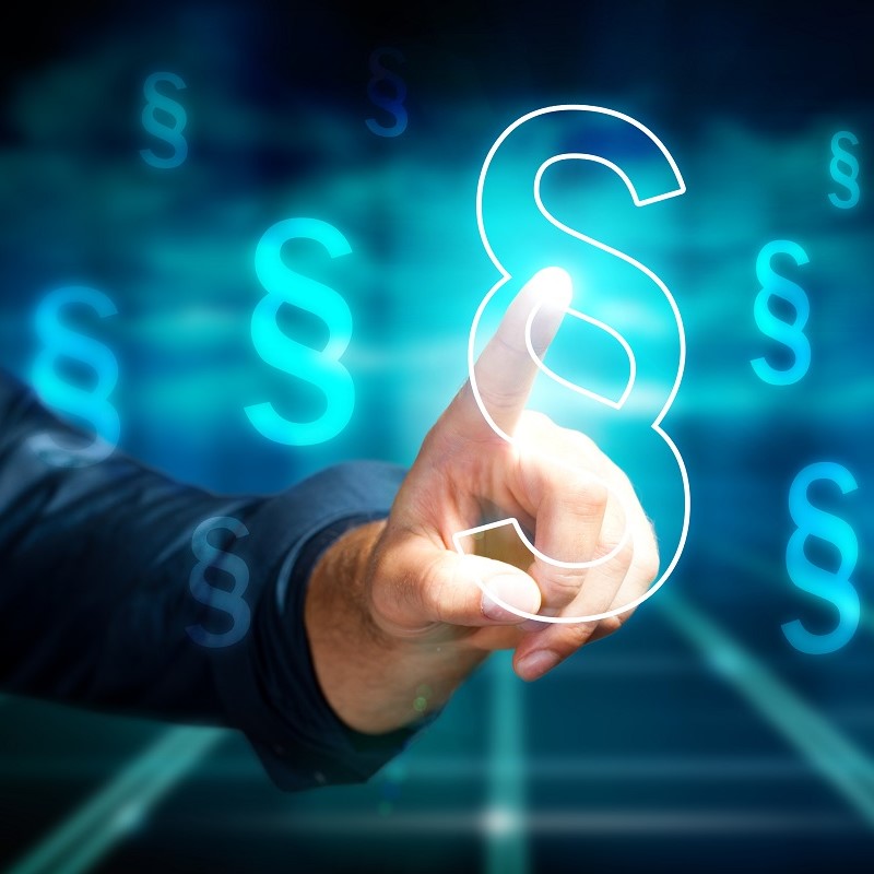 A hand is hovering over a glowing section symbol, surrounded by floating, illuminated version of the same symbol. The image conveys themes of law, legal documents, or legal technology.
