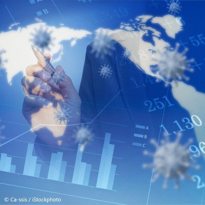 A business professional in a suit holds a pen, poised to write on a digital interface displaying a world map. The background features bar graphs and numerical data, with graphic representations of viruses overlaying the image, suggesting themes of global impact and economic analysis.