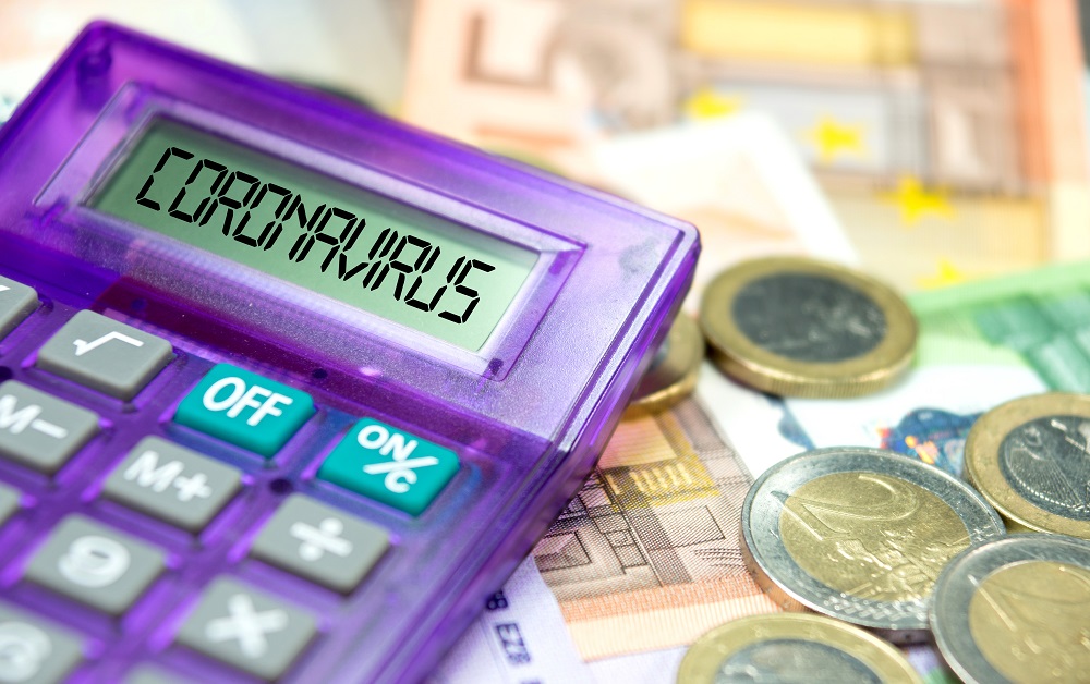 A purple calculator displays the word "CORONAVIRUS" on its screen, surrounded by various Euro banknotes and coins, symbolizing economic impact or calculations related to the pandemic.