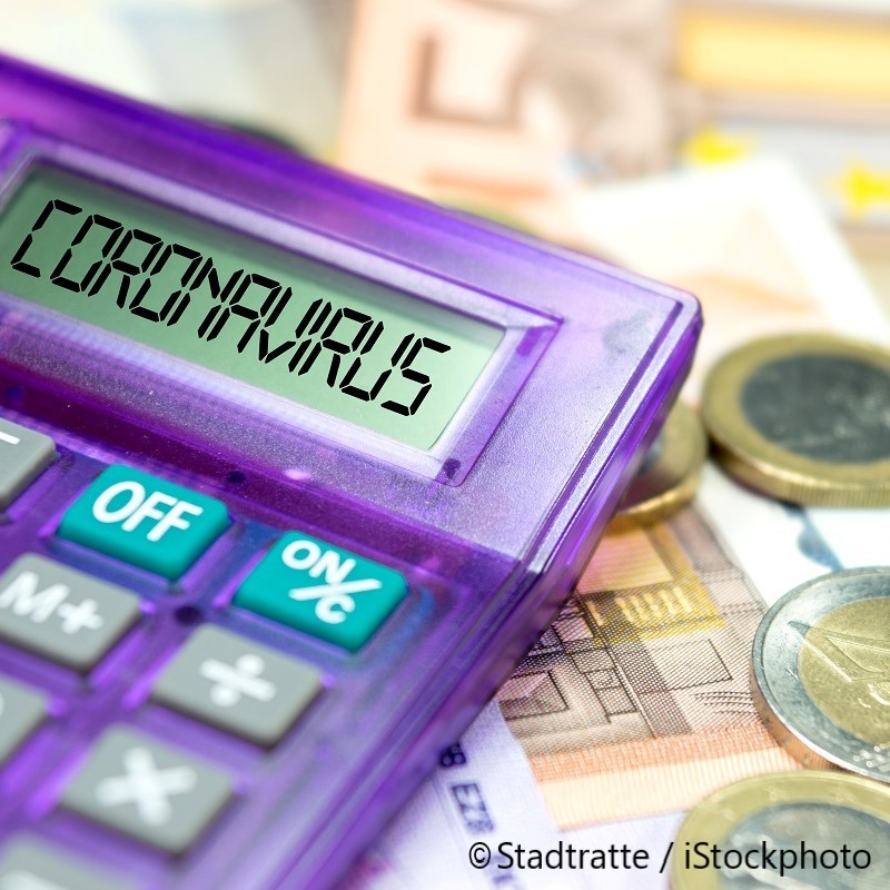 A purple calculator displays the word "CORONAVIRUS" on its screen, surrounded by euro banknotes and coins. The image highlights the impact of the pandemic on finance.