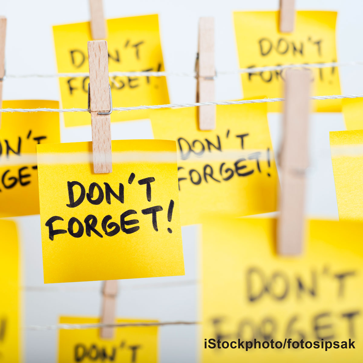 Eine Wäscheleine ist mit zahlreichen gelben Haftnotizen befestigt, auf denen in großen, schwarzen Buchstaben „DON’T FORGET!“ steht. Die Notizen vermitteln die Botschaft, wichtige Dinge nicht zu vergessen.