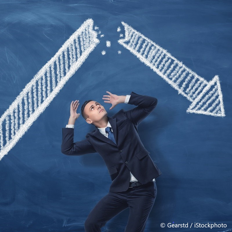 A businessman in a suit looks up with a worried expression as two large upward arrows, drawn in chalk, appear to break through a blue background. The image conveys themes of pressure and unexpected challenges in the business environment.
