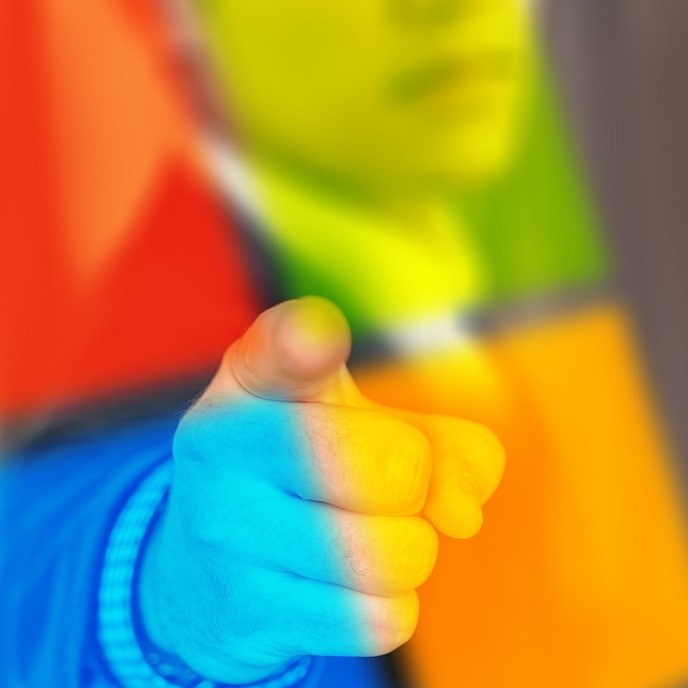 A person's hand is extended forward, finger pointing, suggesting emphasis or action. The background features vibrant colors, creating an abstract and dynamic effect. The focus is on the hand gesture, conveying a sense of authority or engagement.