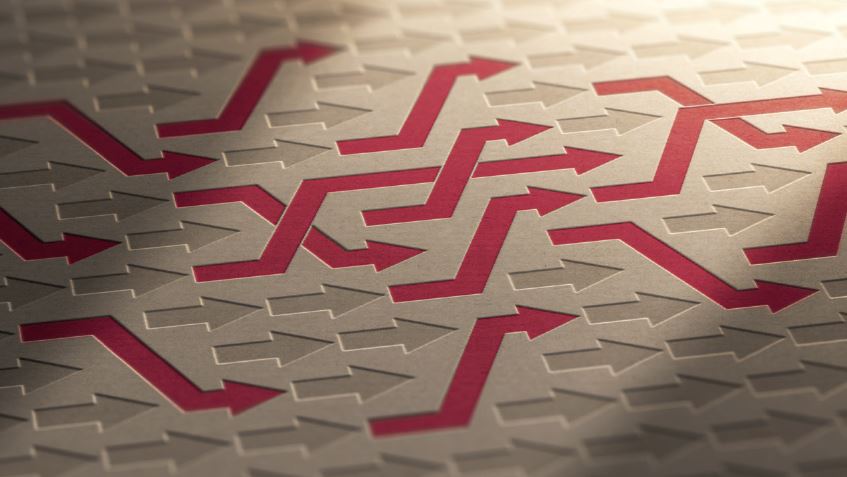 The image features a textured surface with various arrows in a zigzag pattern, predominantly in red against a beige background. The arrows point in different directions, creating a complex design that symbolizes movement and direction.