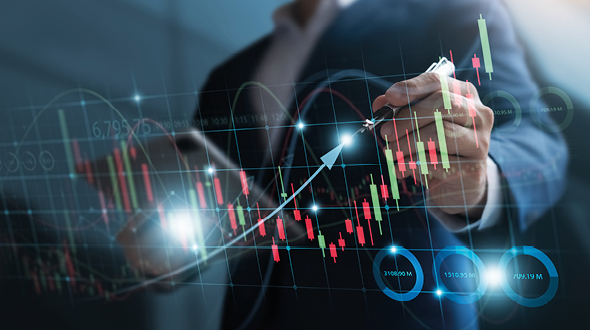 Ein Geschäftsmann trägt mit einem Stift auf einem digitalen Diagramm von Kursbewegungen eine steigende Linie ein. Die Grafik zeigt farbige Balken und Linien, die verschiedene Werte repräsentieren, während Zahlen und Datenpunkte hervorgehoben werden.